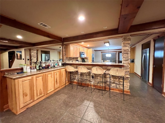 kitchen with beamed ceiling, a breakfast bar, kitchen peninsula, backsplash, and appliances with stainless steel finishes