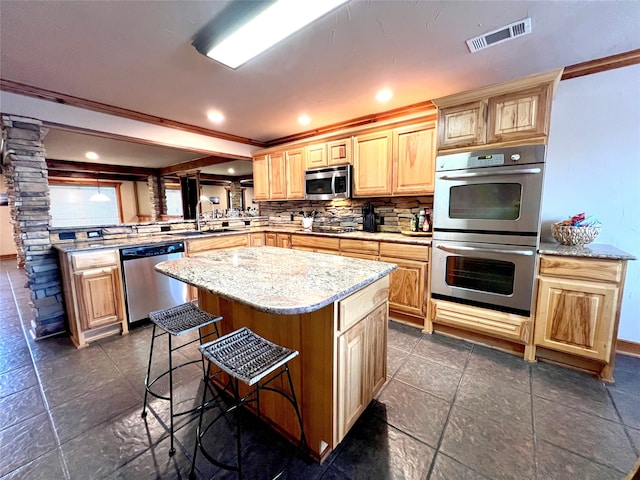 kitchen featuring tasteful backsplash, a kitchen island, a kitchen breakfast bar, kitchen peninsula, and appliances with stainless steel finishes