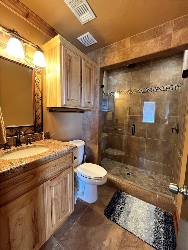 bathroom with vanity, toilet, a shower with door, and tile patterned floors