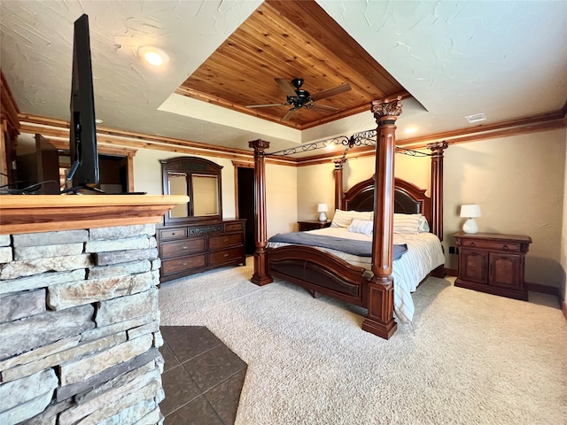 bedroom with a raised ceiling, crown molding, carpet flooring, and decorative columns