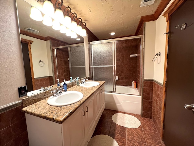 bathroom with vanity, bath / shower combo with glass door, tile walls, tile patterned floors, and a textured ceiling