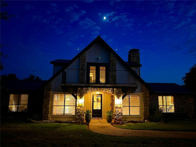 view of front of home with a balcony and a yard