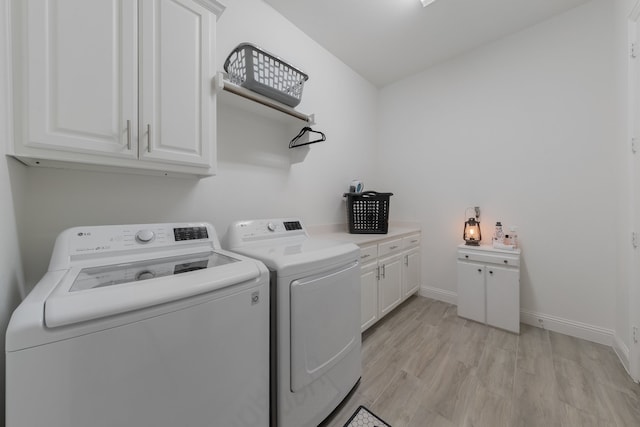 laundry room featuring independent washer and dryer, cabinets, and light hardwood / wood-style flooring