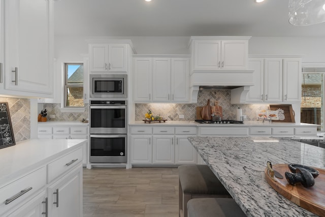 kitchen with pendant lighting, stainless steel appliances, decorative backsplash, and white cabinetry