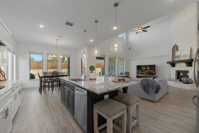 kitchen with an island with sink, sink, ceiling fan with notable chandelier, white cabinetry, and dishwasher