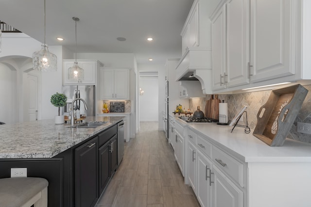 kitchen with appliances with stainless steel finishes, decorative light fixtures, sink, and white cabinetry