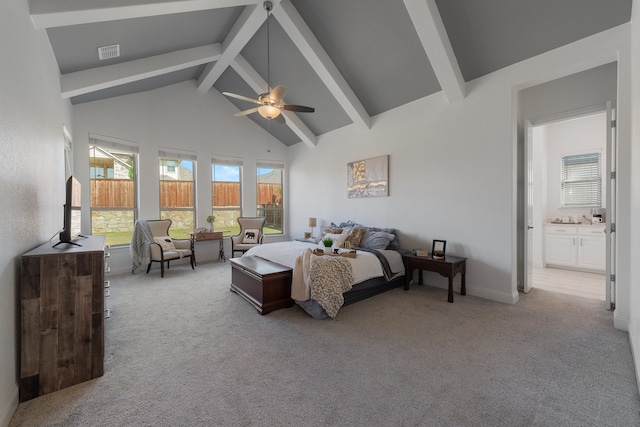 bedroom featuring ceiling fan, light carpet, beamed ceiling, and ensuite bath