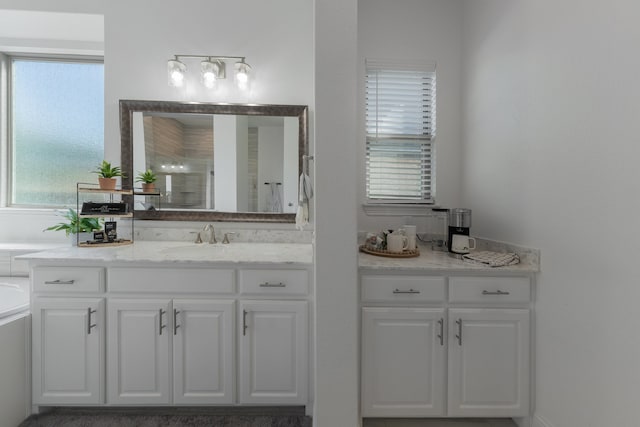 bathroom featuring independent shower and bath, vanity, and a healthy amount of sunlight