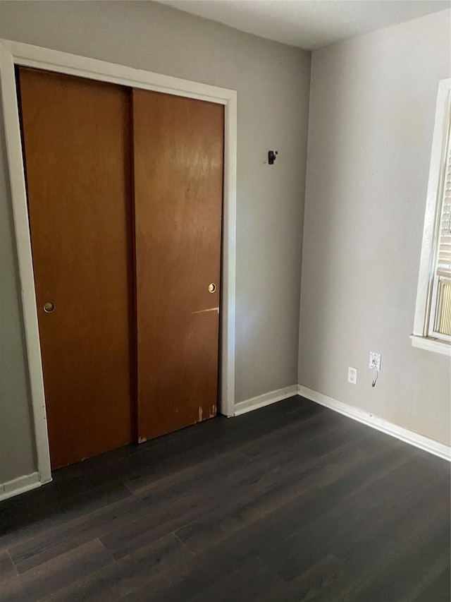 unfurnished bedroom featuring a closet and dark wood-type flooring