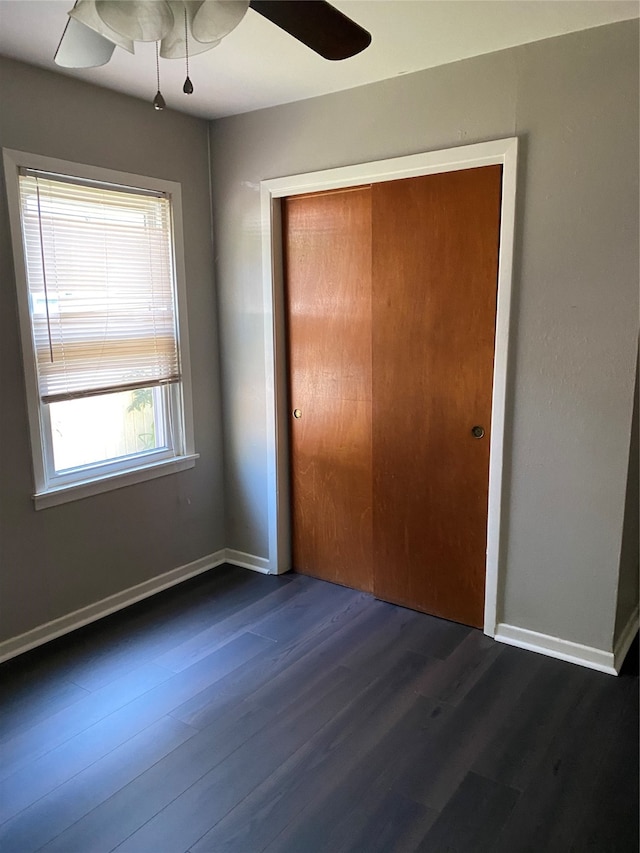 unfurnished bedroom featuring a closet, dark hardwood / wood-style floors, and ceiling fan