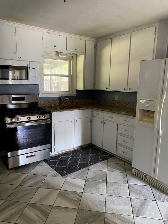 kitchen featuring white appliances, white cabinets, sink, and dark stone counters