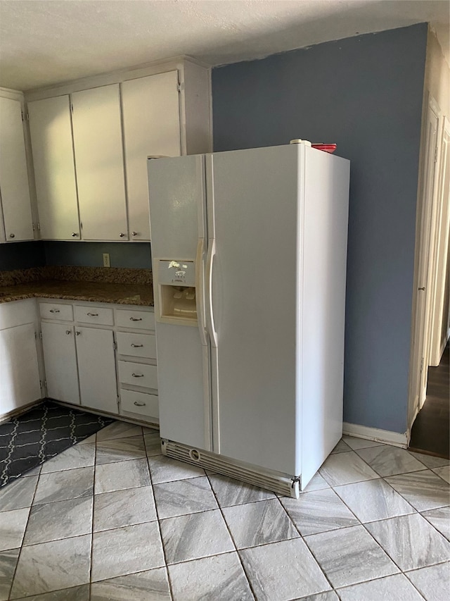 kitchen with white cabinets, a textured ceiling, and white refrigerator with ice dispenser