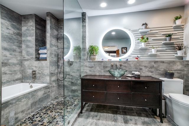 full bathroom featuring vanity, tile walls, toilet, and independent shower and bath