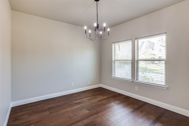 unfurnished room with a notable chandelier and dark wood-type flooring