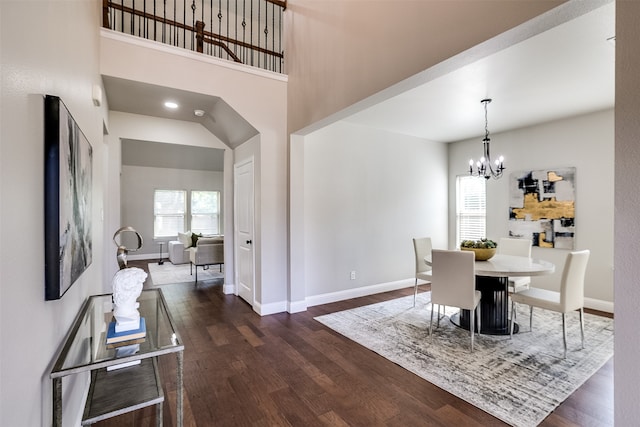 dining room featuring dark wood-type flooring, a high ceiling, and a chandelier