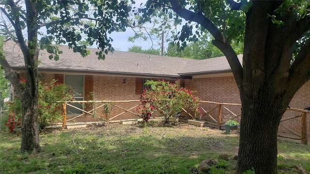 rear view of property featuring roof with shingles and brick siding