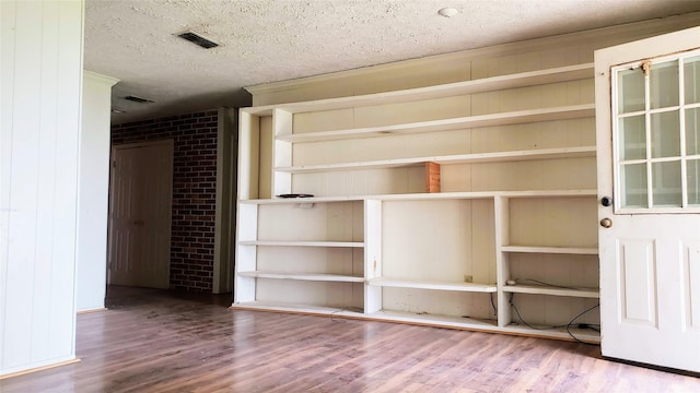 unfurnished room featuring visible vents, a textured ceiling, and wood finished floors