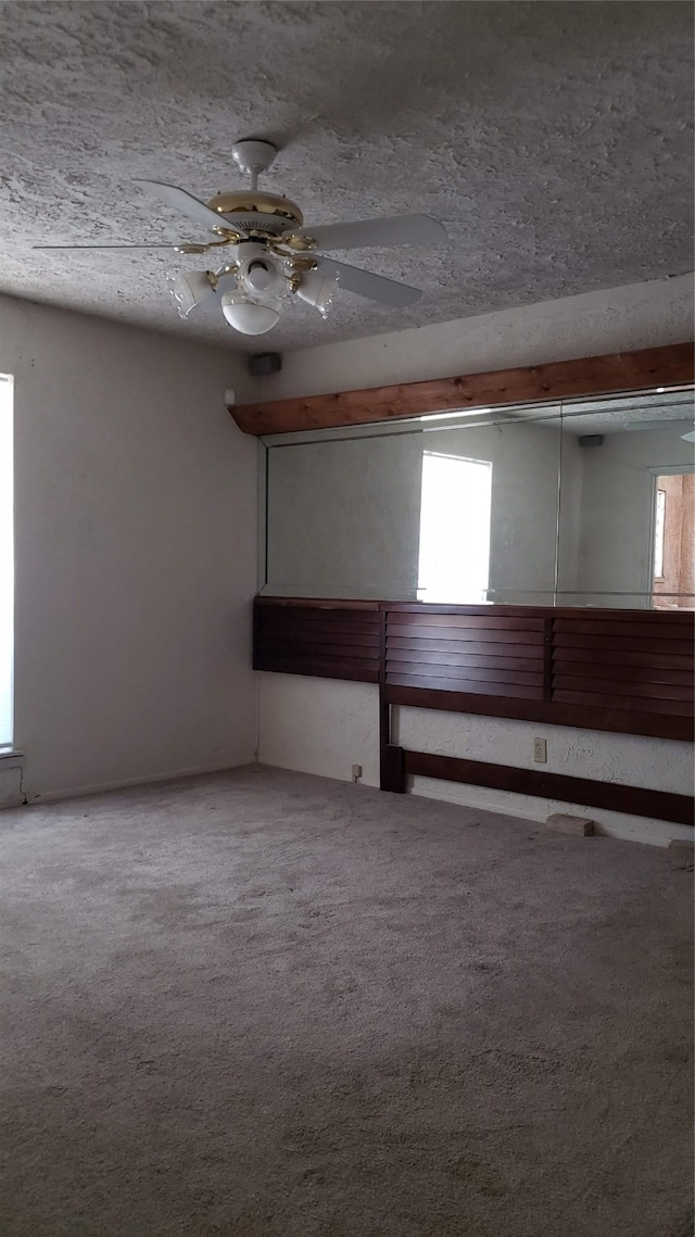 carpeted empty room featuring ceiling fan and a textured ceiling