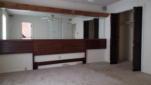 unfurnished bedroom with ceiling fan, light colored carpet, a textured ceiling, and a closet