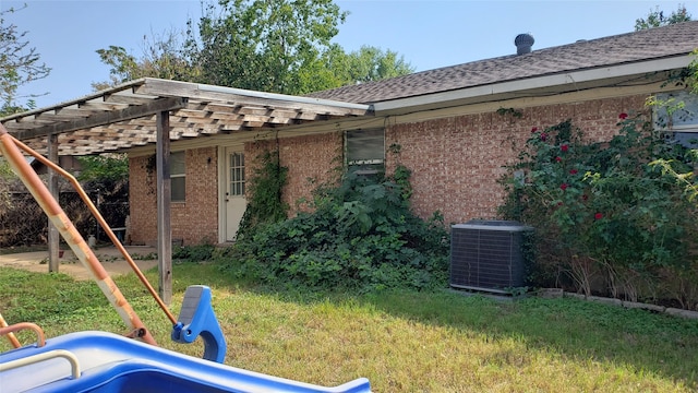 back of house featuring a yard, central AC, and a pergola