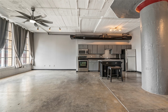 kitchen with ceiling fan, a breakfast bar, sink, appliances with stainless steel finishes, and gray cabinets