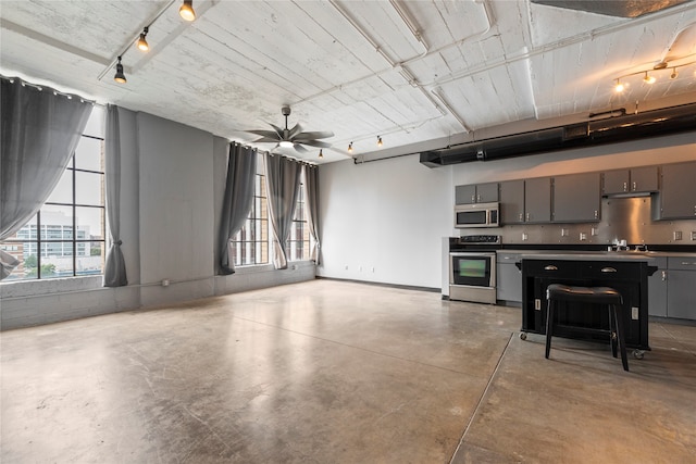 kitchen featuring track lighting, ceiling fan, a breakfast bar area, and stainless steel appliances