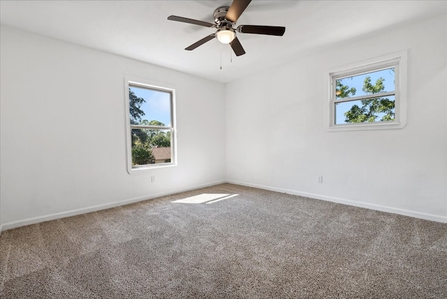 empty room with ceiling fan, a wealth of natural light, and carpet floors