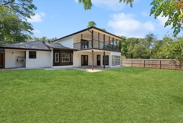 rear view of house featuring a yard, a balcony, and a patio area