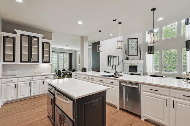 kitchen featuring sink, stainless steel dishwasher, hanging light fixtures, and a kitchen island