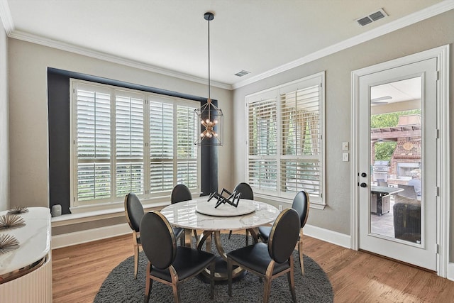 dining room with ornamental molding, a healthy amount of sunlight, and light wood-type flooring