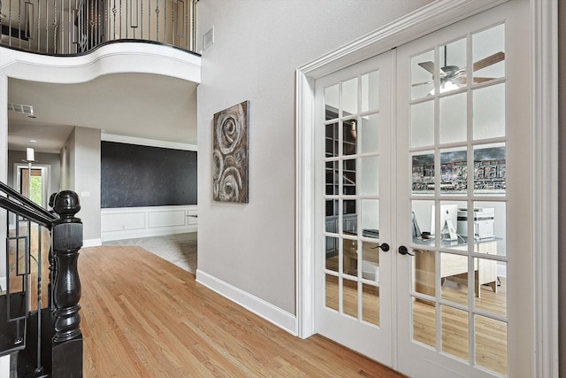 interior space featuring wood-type flooring, a towering ceiling, ceiling fan, and french doors