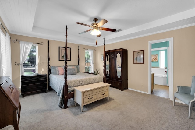 bedroom with ceiling fan, light carpet, connected bathroom, a tray ceiling, and ornamental molding