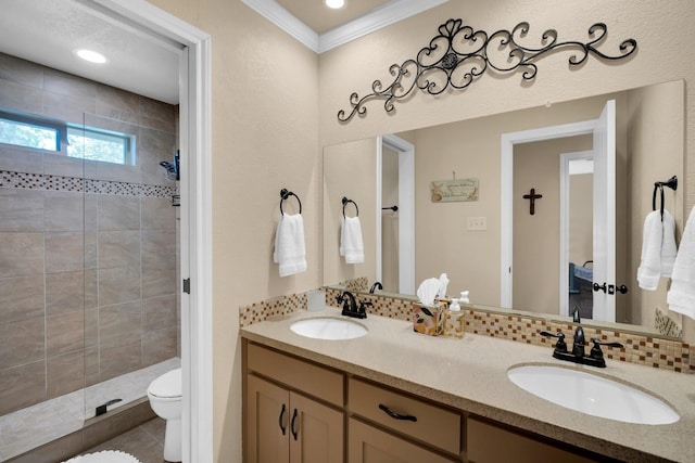 bathroom with crown molding, tiled shower, vanity, and toilet