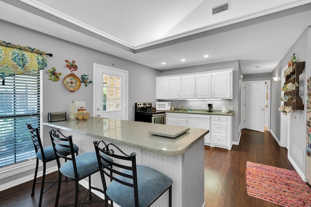 kitchen featuring white cabinets, kitchen peninsula, white appliances, dark hardwood / wood-style floors, and a breakfast bar