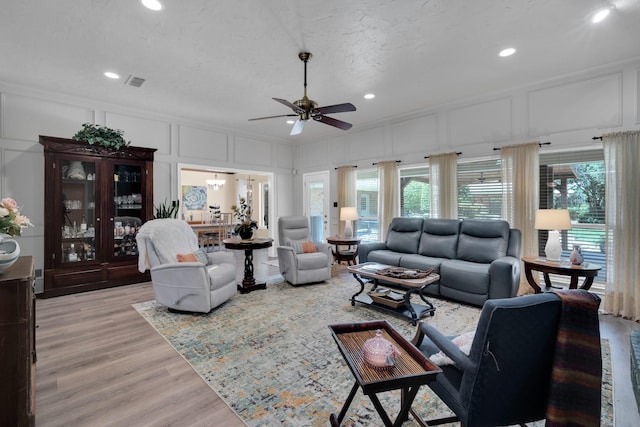 living room featuring crown molding, ceiling fan, light hardwood / wood-style floors, and a textured ceiling