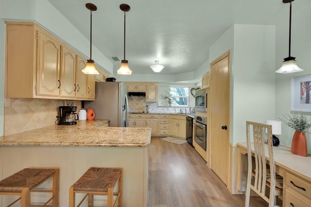 kitchen with kitchen peninsula, backsplash, stainless steel appliances, a breakfast bar, and light hardwood / wood-style floors