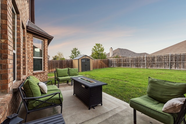 patio terrace at dusk featuring an outdoor living space with a fire pit, a storage unit, and a lawn