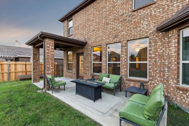 patio terrace at dusk with a yard and an outdoor living space with a fire pit