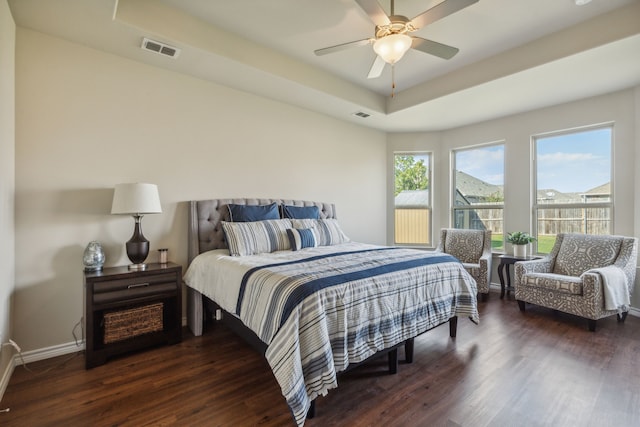 bedroom featuring ceiling fan, dark hardwood / wood-style flooring, and a tray ceiling