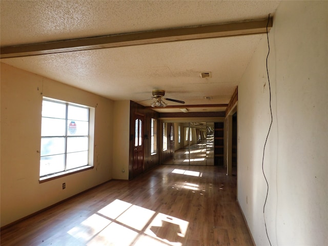 interior space with beam ceiling, dark hardwood / wood-style flooring, a textured ceiling, and ceiling fan