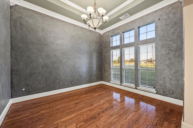 empty room with hardwood / wood-style flooring, ornamental molding, an inviting chandelier, and a tray ceiling