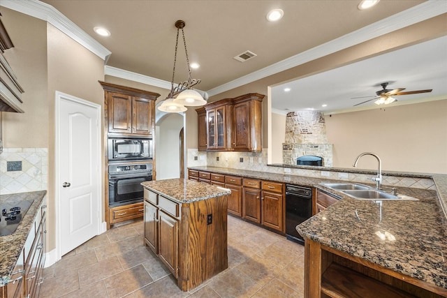 kitchen featuring sink, black appliances, hanging light fixtures, a kitchen island, and backsplash