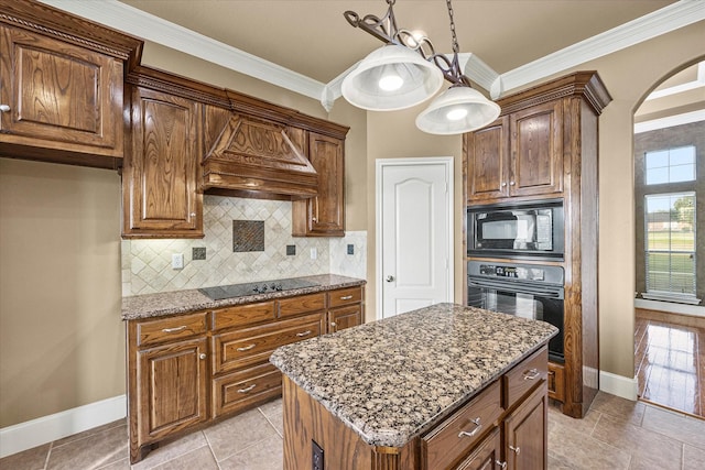 kitchen featuring dark stone countertops, ornamental molding, black appliances, custom range hood, and a kitchen island