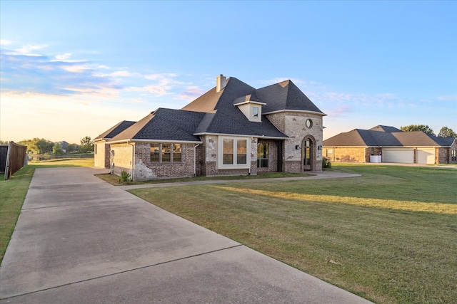 french country inspired facade with a garage and a lawn