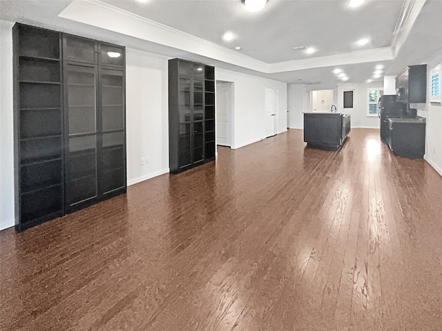 unfurnished living room with a tray ceiling, dark hardwood / wood-style floors, and crown molding