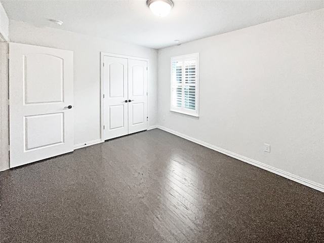 unfurnished bedroom featuring a closet and dark hardwood / wood-style floors