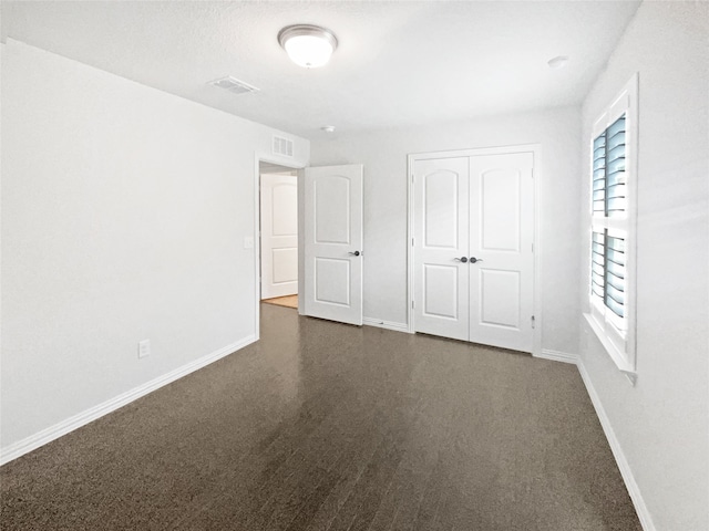 unfurnished bedroom with a closet and dark colored carpet