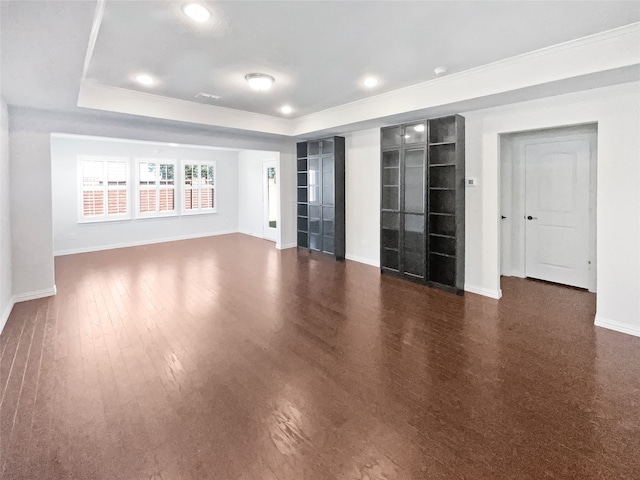 spare room with dark wood-type flooring and a raised ceiling