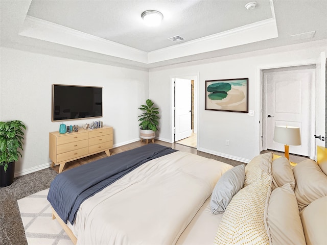 bedroom featuring carpet flooring, a textured ceiling, a tray ceiling, and ornamental molding