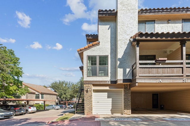 exterior space with a carport, a balcony, and a garage